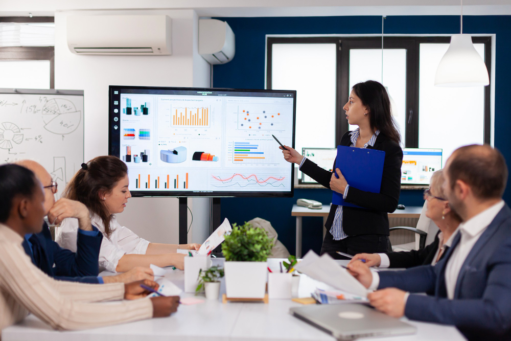 young-team-leader-big-corporation-briefing-coworkers-pointing-graph-meeting-corporate-staff (1)